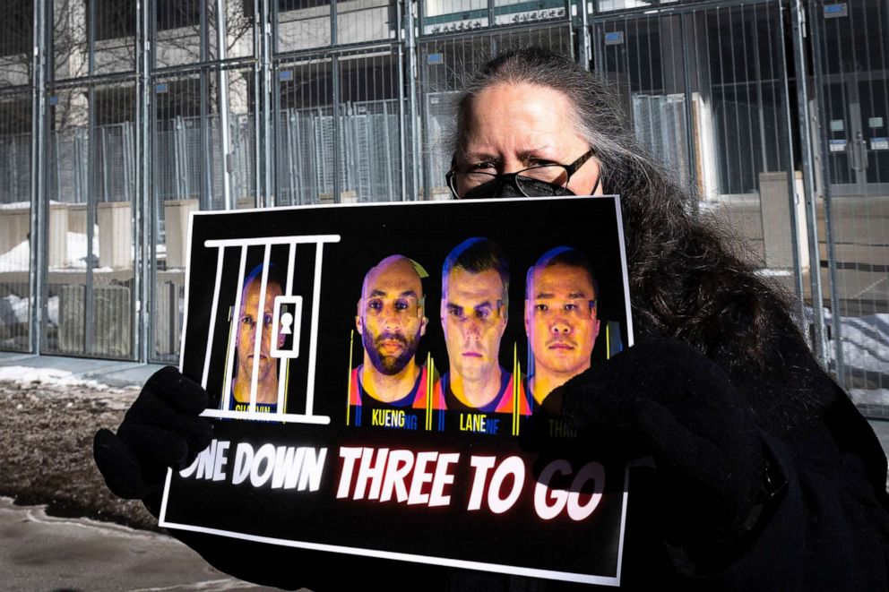 PHOTO: A community activist holds a placard displaying images of J. Alexander Kueng, Thomas Lane and Tou Thao., who were charged with federal civil rights violations in George Floyd's death outside the US District Court in St. Paul, Minn., Jan. 20, 2022.