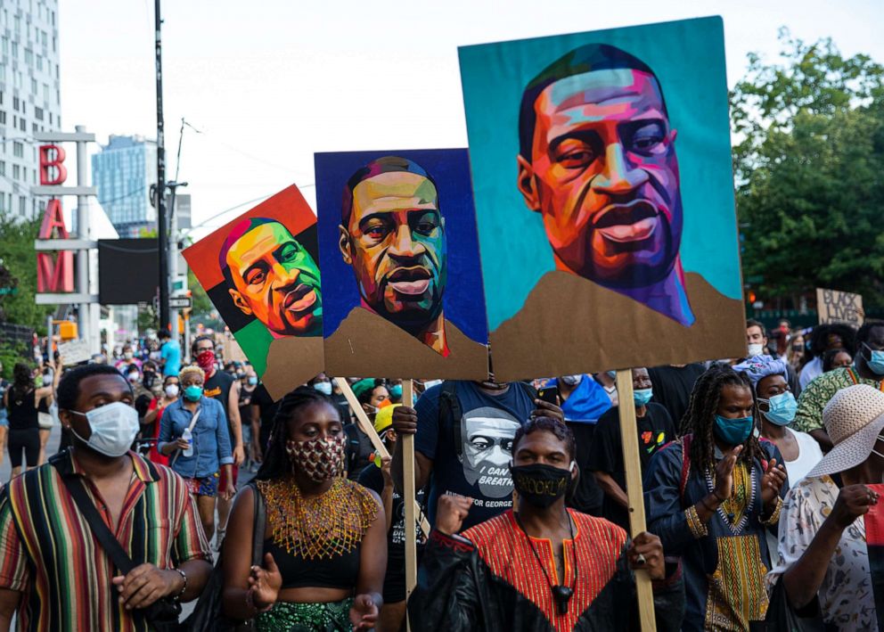 PHOTO: Pedestrians carry posters with the picture of George Floyd who was killed in police custody in Minneapolis, during a protest march in the Brooklyn borough of New York, June 19, 2020.