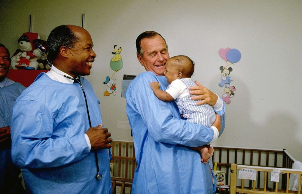 PHOTO: President George H.W. Bush holds a baby that was diagnosed with AIDS while the Secretary of Health and Human Services, Louis Sullivan, looks on, in 1989.