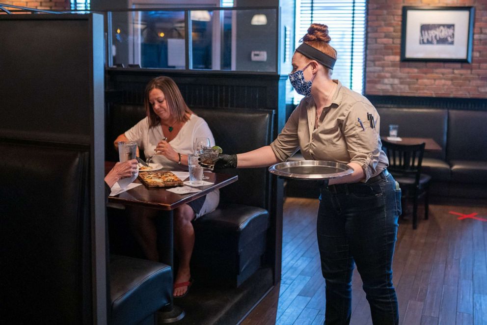 PHOTO: An employee wearing a protective mask and gloves serves a customer a drink at a Marlow's Tavern restaurant in Johns Creek, Georgia, May 6, 2020.