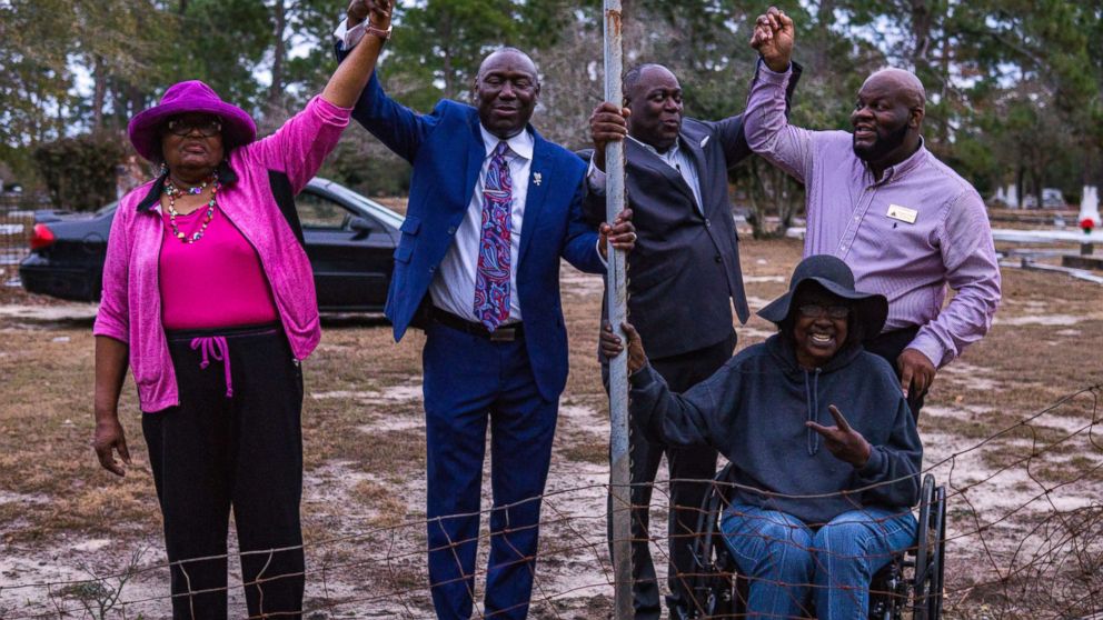 PHOTO: From left, Priscilla Davis, Ben Crump, Mayor Rufus Davis, Gwen Lillian Thomas, and Councilman Venterra Pollard hold hands in victory at a small portion of the fence left to be removed at Oakview Cemetery in Camilla, Ga., Jan. 11, 2018.