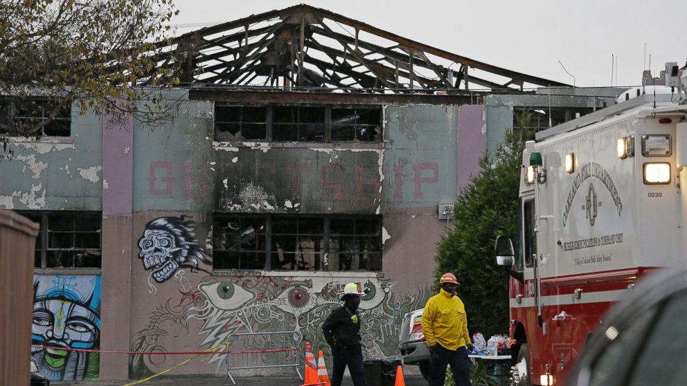In this Dec. 7, 2016 file photo, Oakland fire officials walk past the remains of the Ghost Ship warehouse damaged from a deadly fire in Oakland, Calif.