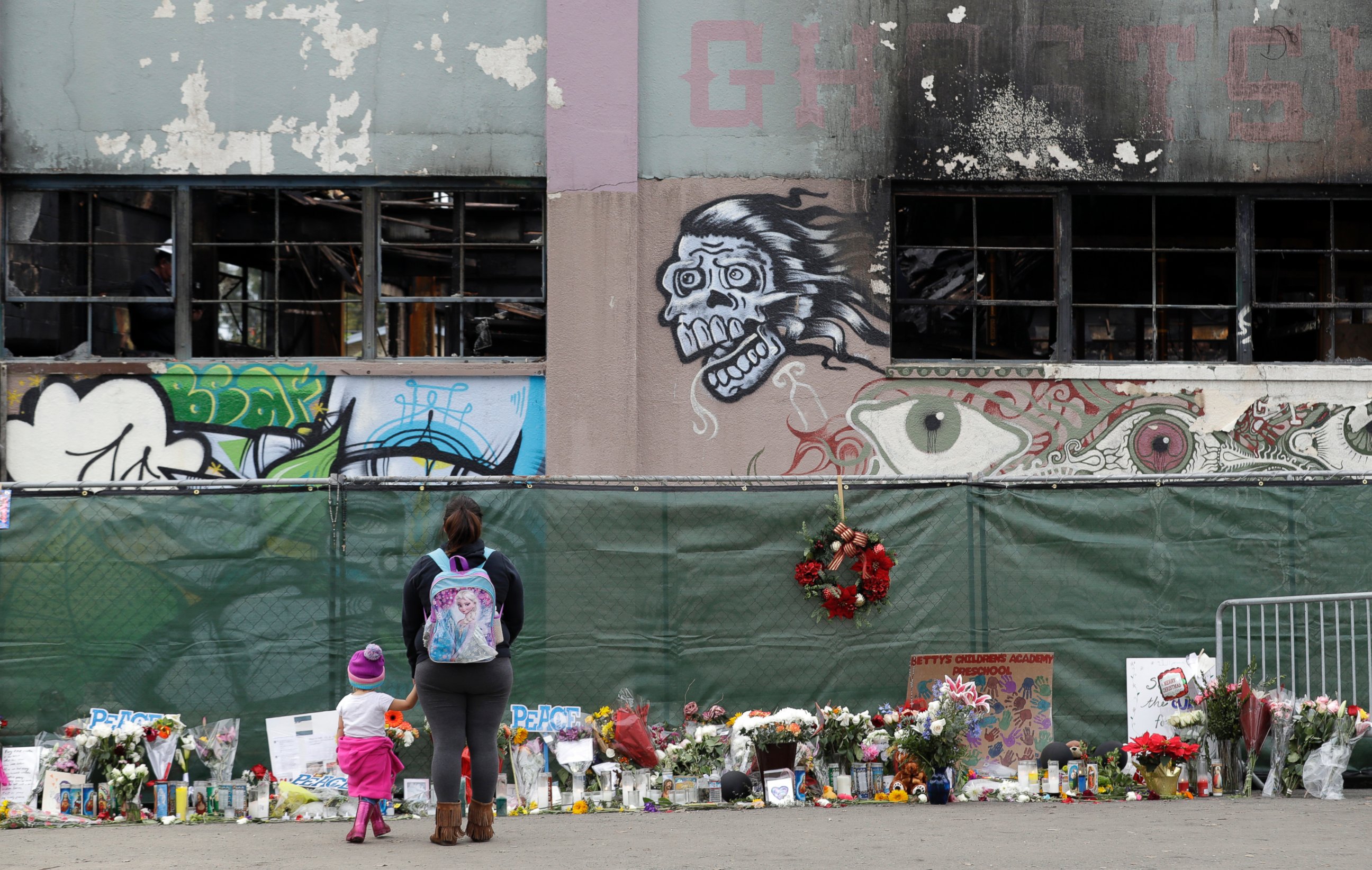 This Dec. 13, 2016 file photo shows flowers, pictures, signs and candles, are placed at the scene of a warehouse fire in Oakland, Calif.