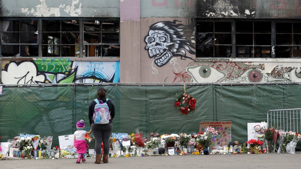 This Dec. 13, 2016 file photo shows flowers, pictures, signs and candles, are placed at the scene of a warehouse fire in Oakland, Calif.