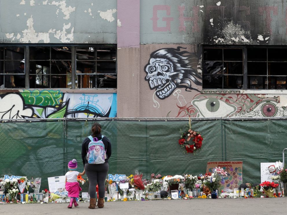 This Dec. 13, 2016 file photo shows flowers, pictures, signs and candles, are placed at the scene of a warehouse fire in Oakland, Calif.