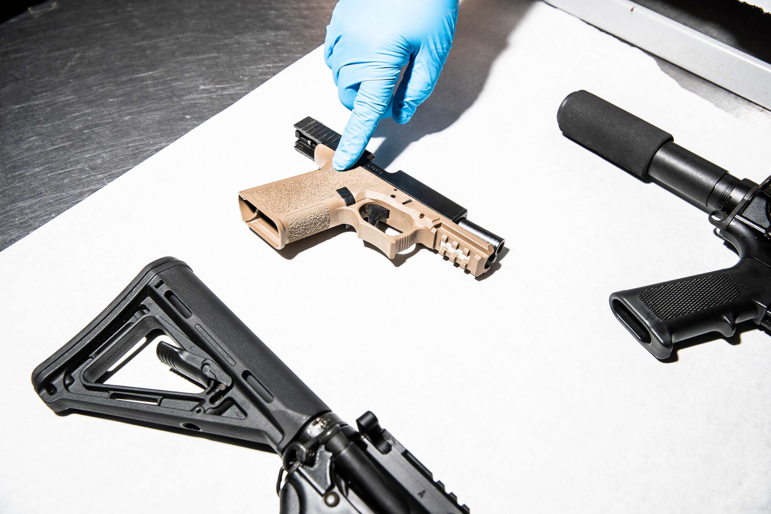 PHOTO: In this April 15, 2021, file photo, a police service technician points to a semi-automatic pistol assembled with a 80% lower frame from a sample of seized ghost guns, at the department's headquarters in Oakland, Calif.