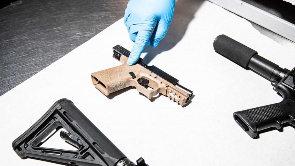 PHOTO: In this April 15, 2021, file photo, a police service technician points to a semi-automatic pistol assembled with a 80% lower frame from a sample of seized ghost guns, at the department's headquarters in Oakland, Calif.
