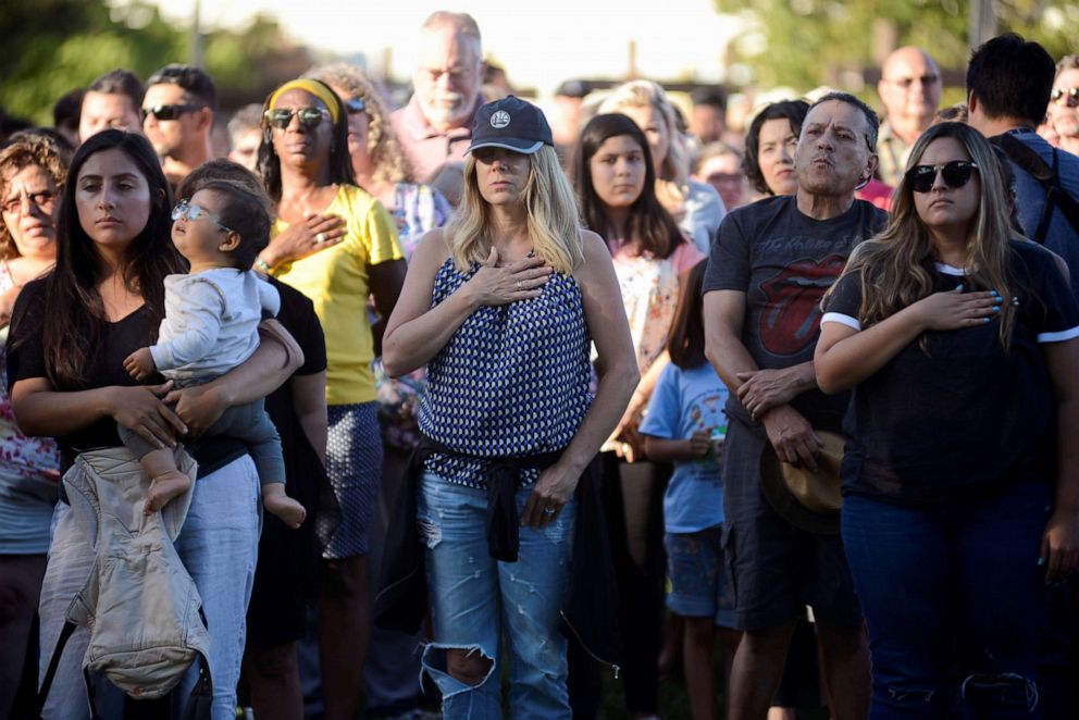 PHOTO: Attendants at a vigil outside of Gilroy City Hall during the singing of the National Anthem honoring those that died and were injured during a mass shooting at the Gilroy Garlic Festival, July 29, 2019, in Gilroy, California.