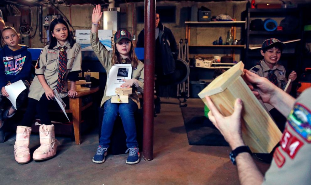 PHOTO: Tatum Weir, center, raises her hand as she prepares to ask a question while going over plans to build a tool box during a cub scout meeting in Madbury, N.H, March 1, 2018. 