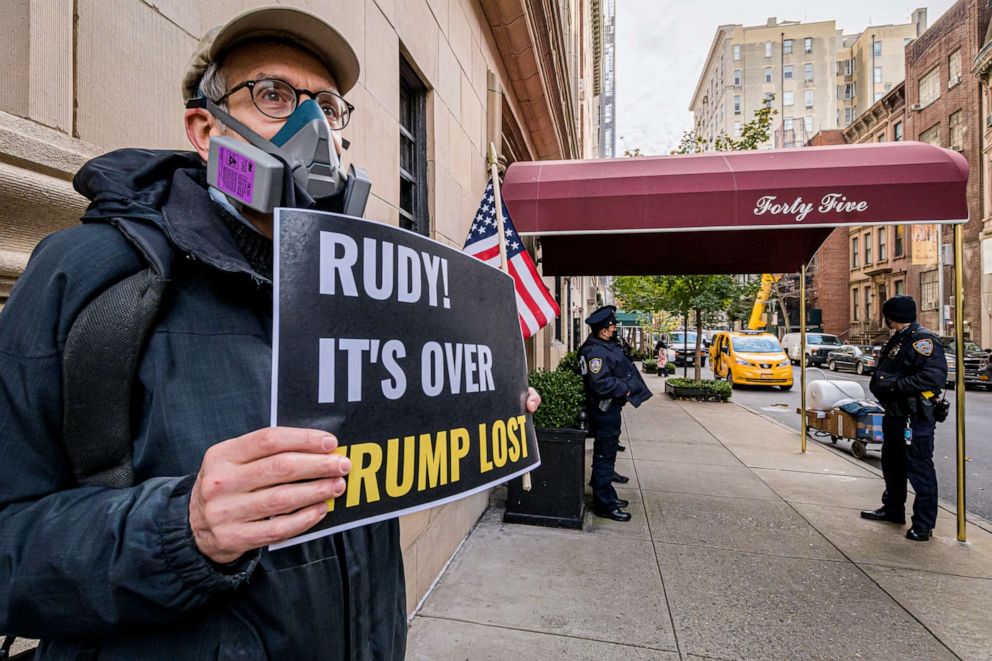 PHOTO: A man holds a sign outside Rudy Giuliani's Upper East Side residence in Manhattan, Nov. 19, 2020.