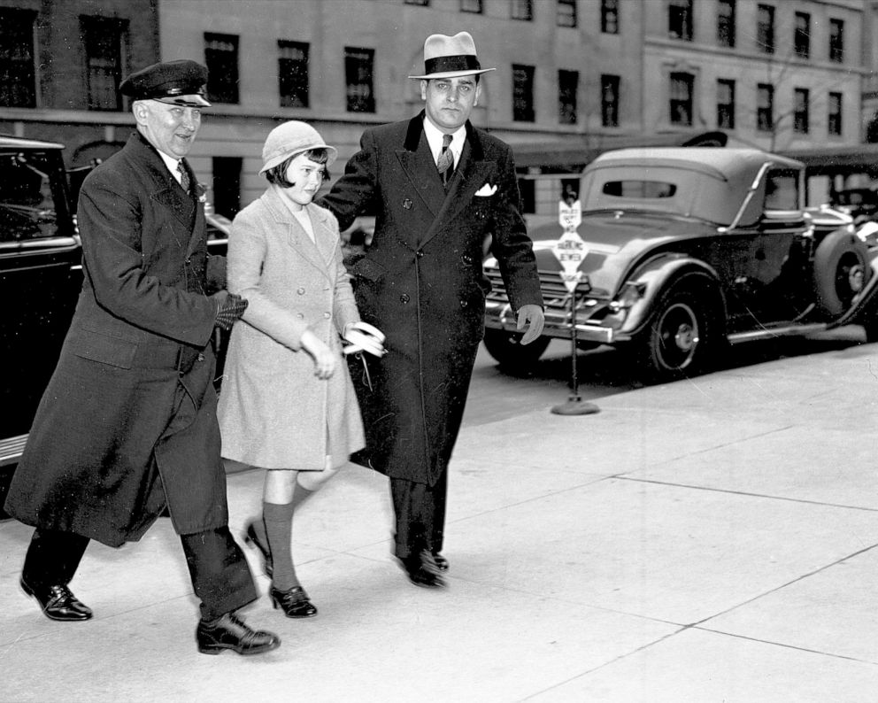 PHOTO:Assisted by chauffeur, Gloria Vanderbilt returns to mother's home after attending Palm Sunday services at Church of St. Francis of Assisi, 
April 14, 1935.