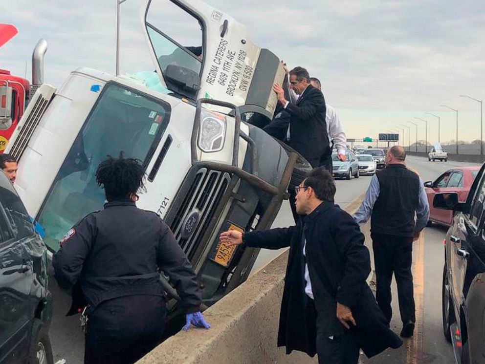 PHOTO: New York Governor Andrew Cuomo stands on a concrete wall and holds open the door to an overturned van on the Brooklyn Queens Expressway, Jan. 6, 2020 in New York.