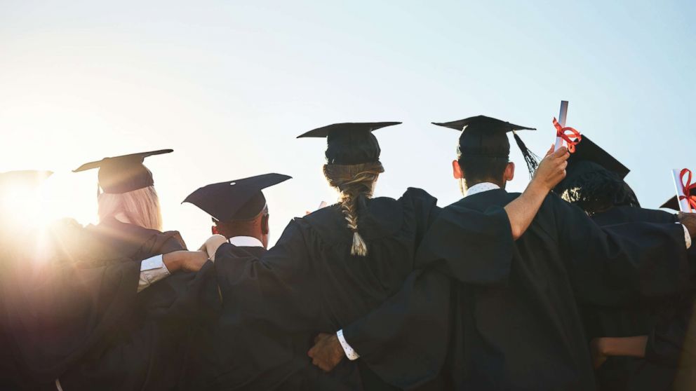 Students standing outside on graduation day in an undated stock photo. 