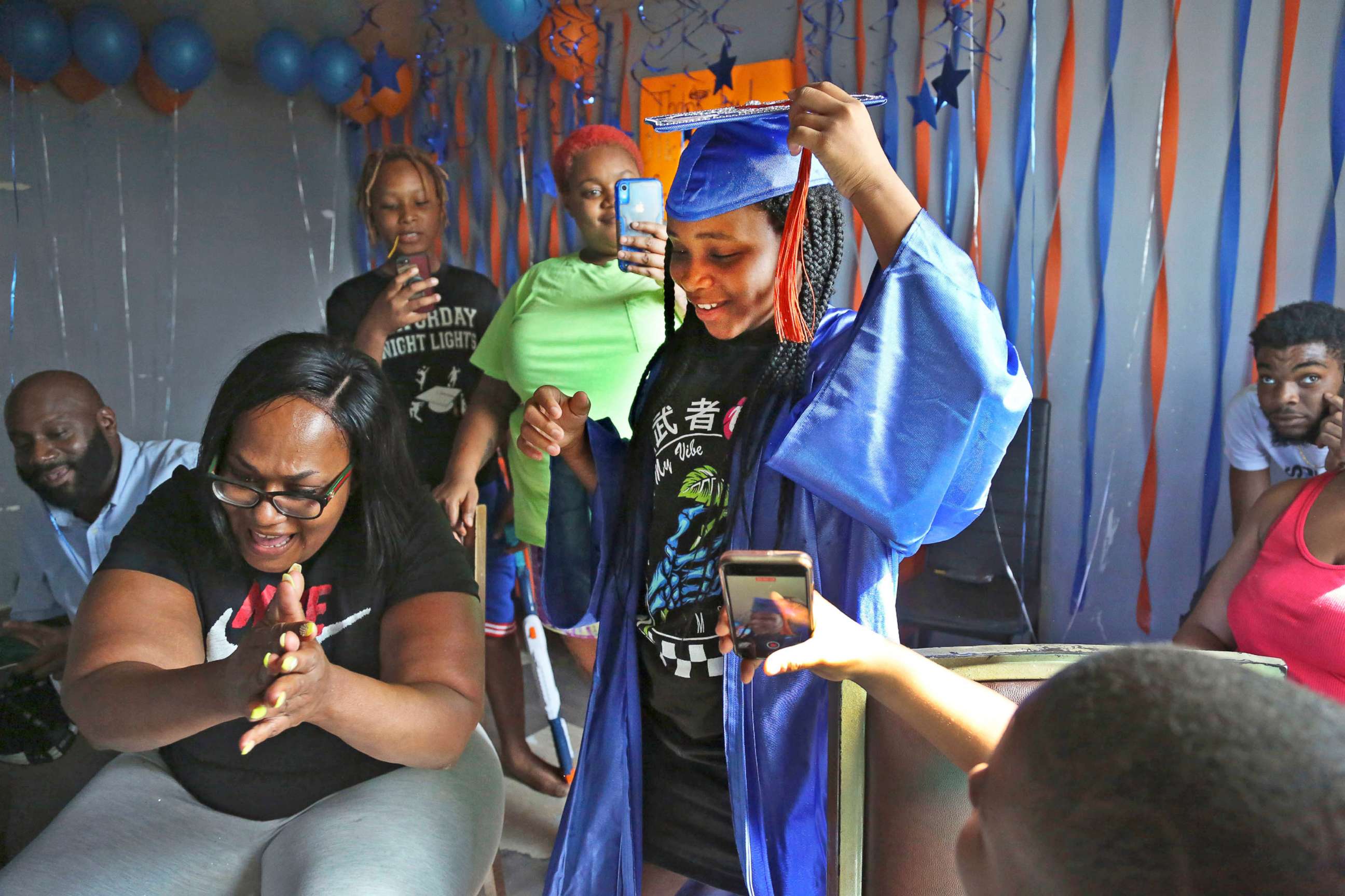 PHOTO: Sharawn Vinson, front left, and family members and friends cheer for her daughter, Maddison Washington, 11, as they watch her virtual graduation from middle school in their apartment in the Brooklyn borough of New York on Aug. 21, 2020.