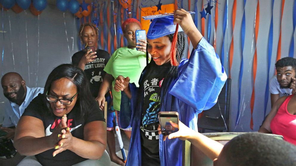 PHOTO: Sharawn Vinson, front left, and family members and friends cheer for her daughter, Maddison Washington, 11, as they watch her virtual graduation from middle school in their apartment in the Brooklyn borough of New York on Aug. 21, 2020.