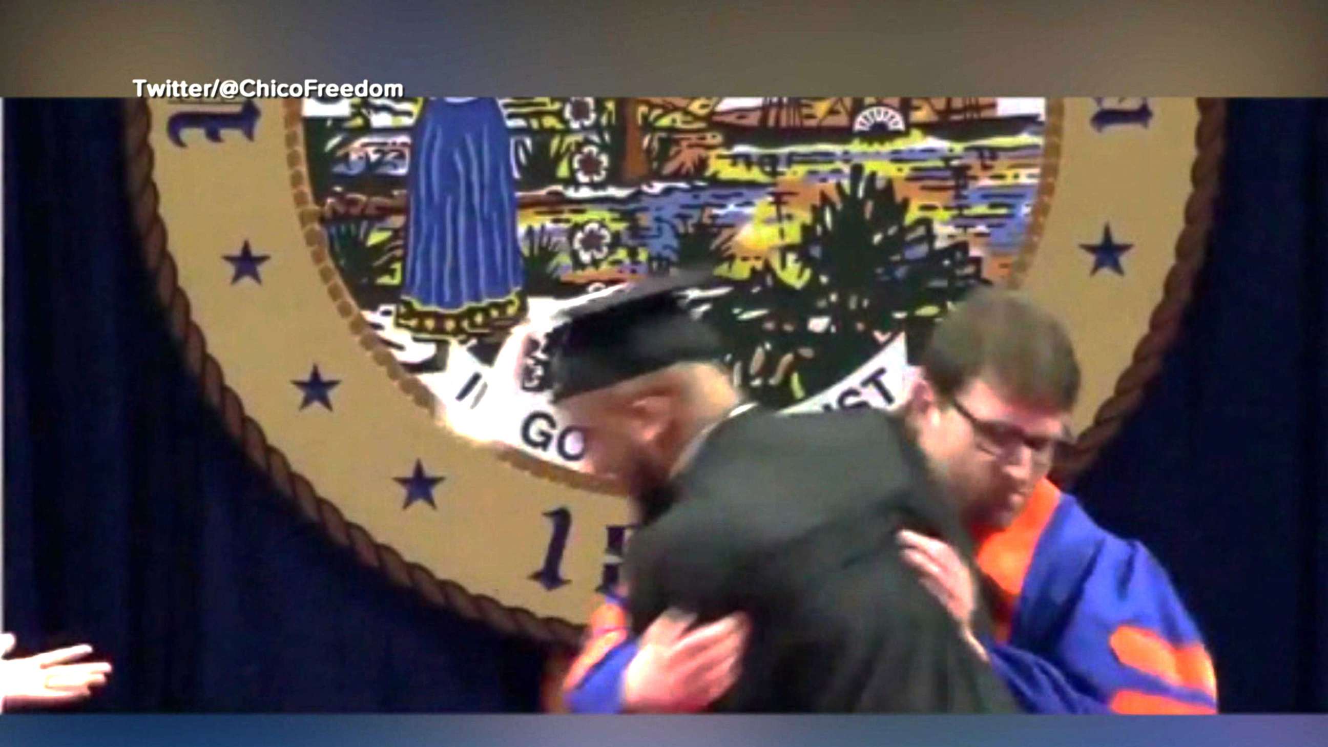 PHOTO: A university usher rushes a student off stage during a commencement ceremony.