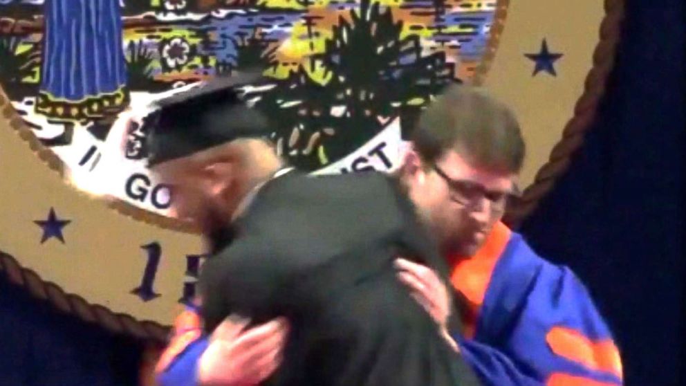 PHOTO: A university usher rushes a student off stage during a commencement ceremony.