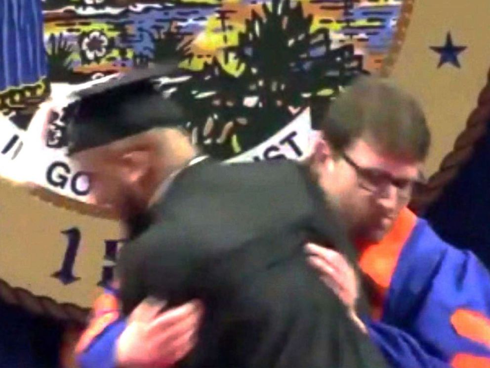 PHOTO: A university usher rushes a student off stage during a commencement ceremony.