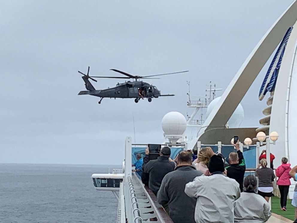 Passengers on board the Grand Princess cruise ship watch while a U.S. military helicopter hovers above the deck, as they approach their original destination of San Francisco, California, on March 5, 2020.