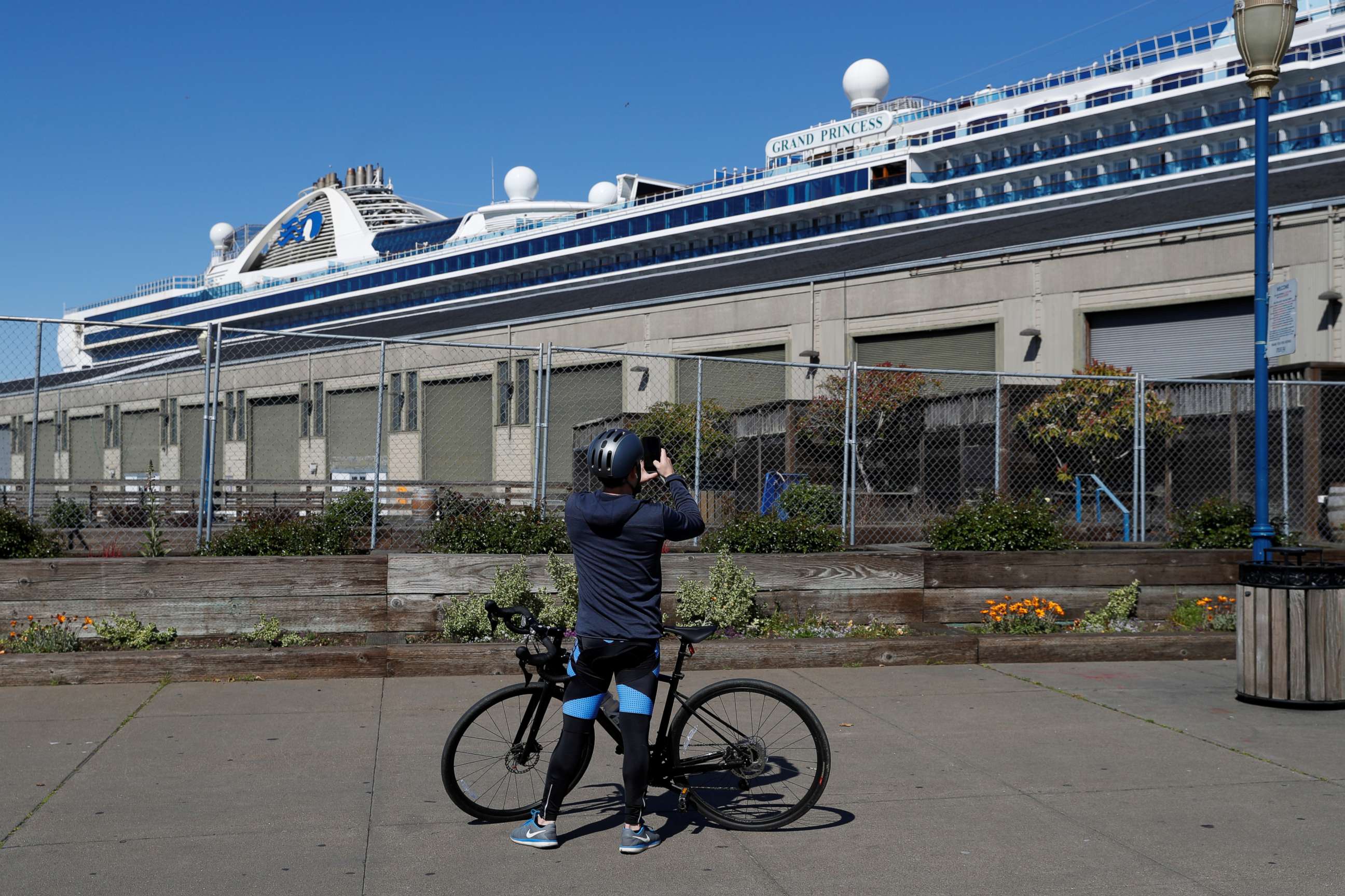 PHOTO: A cyclist takes a photograph of the Grand Princess cruise ship docked at Pier 35 as the spread of COVID-19 continues in San Francisco on April 7, 2020.