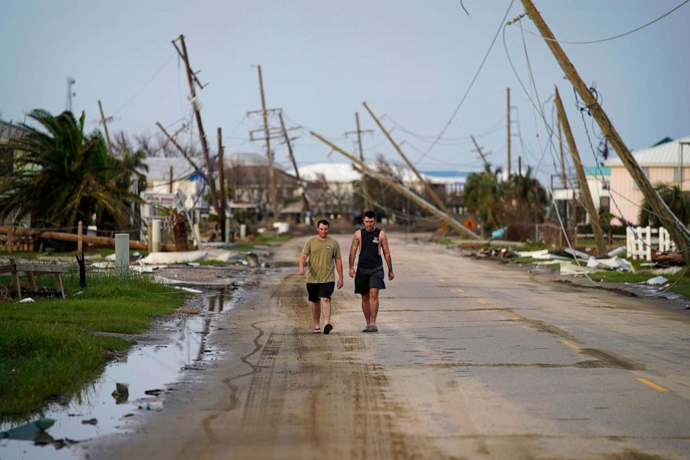 PHOTO: People walk through a neighborhood damaged by Hurricane Ida, Sept. 6, 2021, in Grand Isle, La.