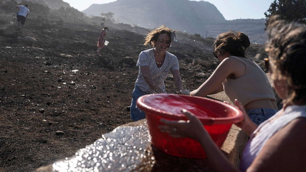 PHOTO: Tourist work with local residents try to extinguish a fire, near the seaside resort of Lindos, on the Aegean Sea island of Rhodes, southeastern Greece, July 24, 2023.