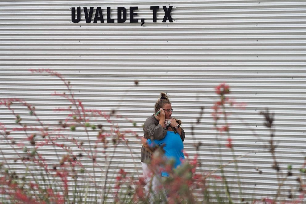 FOTO: Eine Frau weint und umarmt ein junges Mädchen, während sie vor dem Willie de Leon Civic Center telefoniert, wo am 24. Mai 2022 in Uvalde, Texas, Trauerberatung angeboten wird.