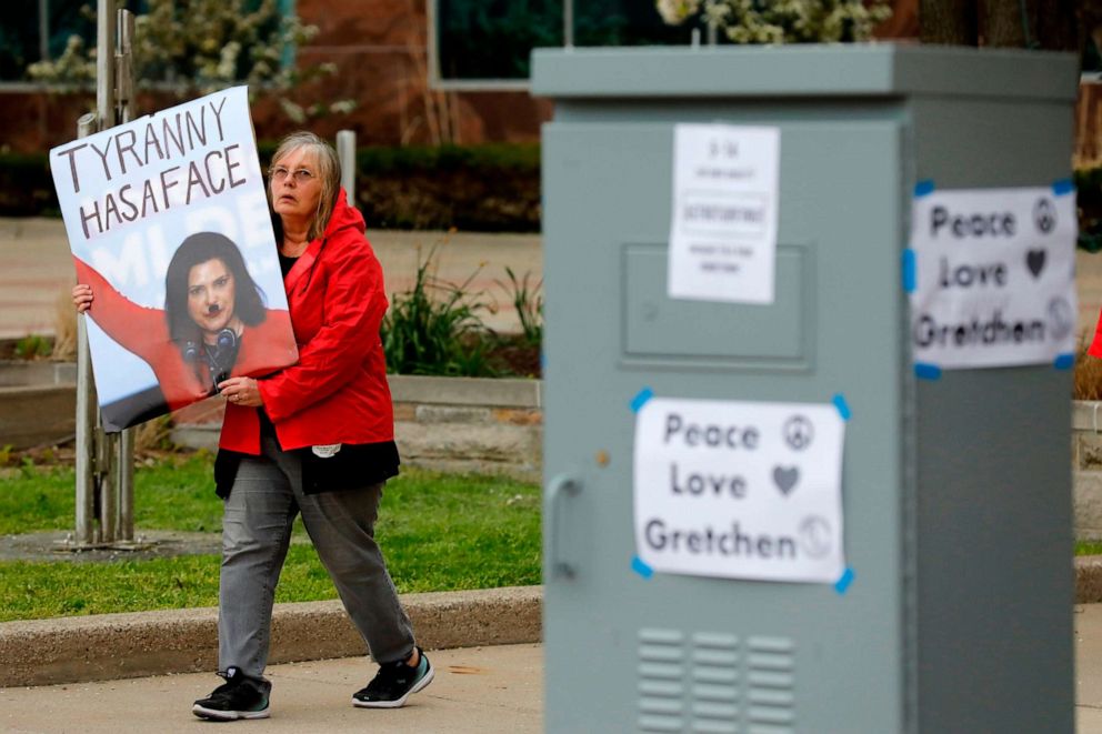 PHOTO: A woman carries a sign critical of Gov. Gretchen Whitmer during a rally in Lansing, Mich., organized by Michigan United for Liberty to protest the coronavirus pandemic stay-at-home order, May 14, 2020.