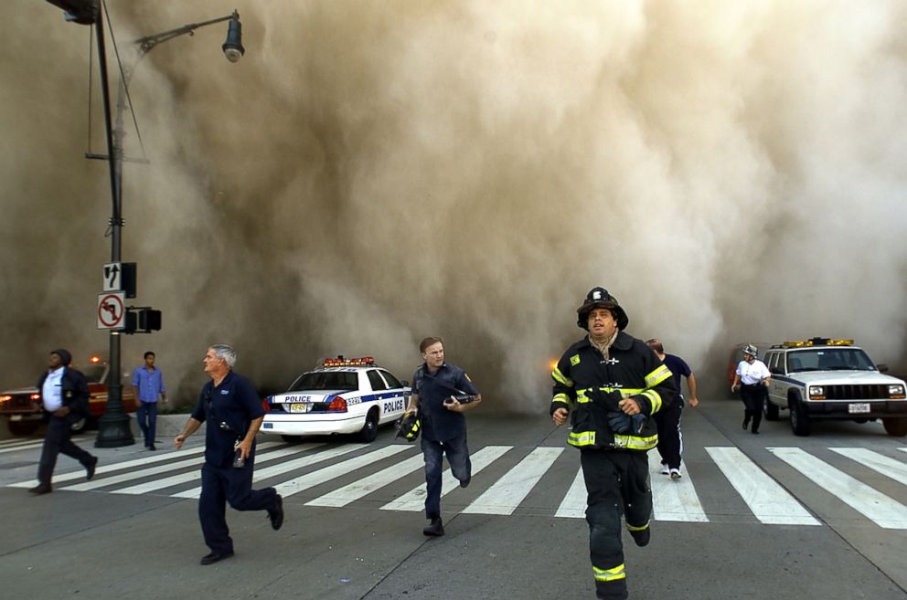 PHOTO: Police and firefighters flee the huge dust cloud caused by the collapse of World Trade Center Tower 1 after terrorists crushed two hijacked planes in the Twin Towers on September 11, 2001 in New York York.