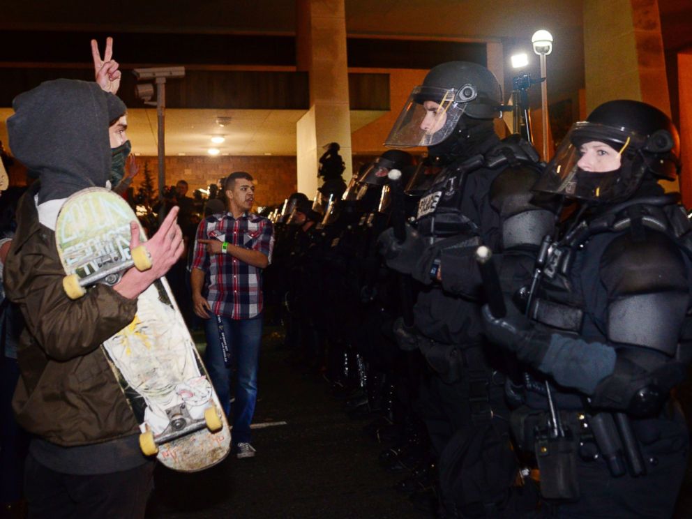 PHOTO: A protestor gestures at police at Pioneer Square in Portland, Oregon on November 11, 2016, to protest the election of US President-elect Donald Trump.
