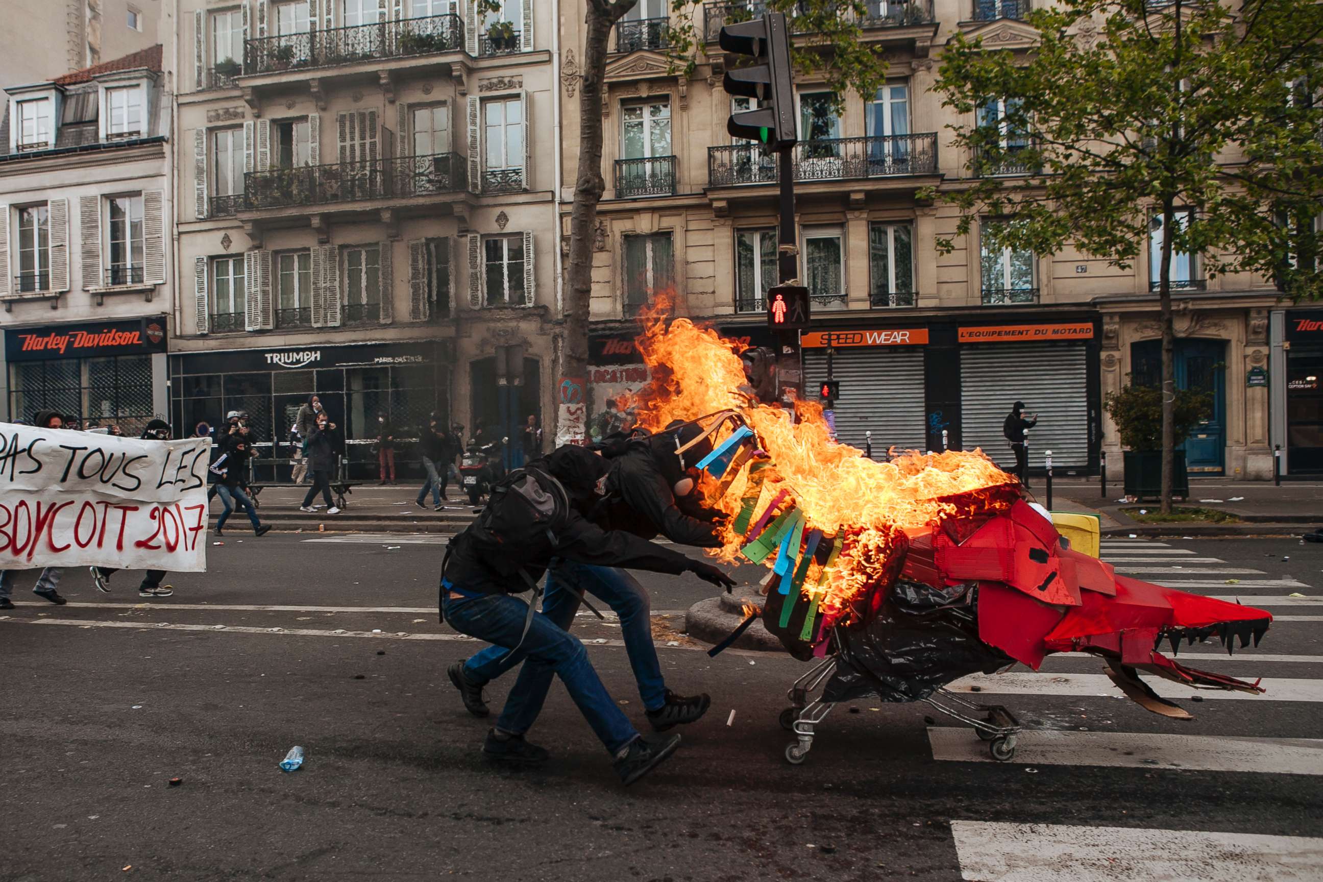 PHOTO: Black Bloc protesters push a shopping trolley with a cardboard dragon face towards police force during the May Day marches in Paris, May, 1, 2017.