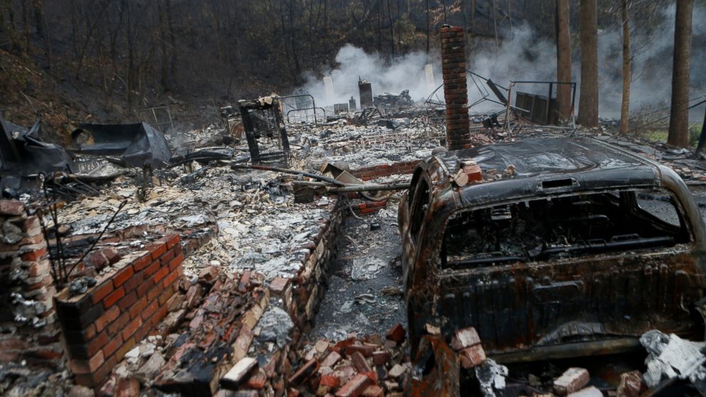 The remains of a home smolder in the wake of a wildfire, Nov. 30, 2016, in Gatlinburg, Tennessee.