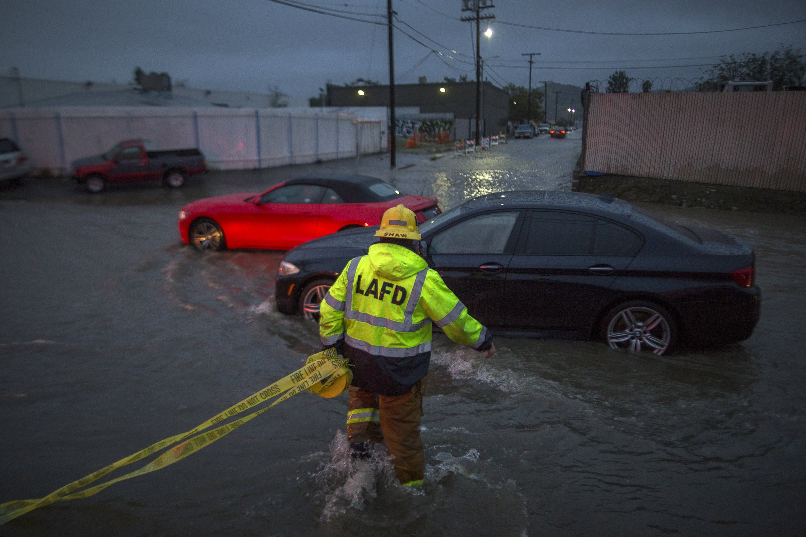 PHOTO: A firefighter carries caution tape in a flooded street as a powerful storm moves across Southern California Feb. 17, 2017, in Sun Valley, California. 