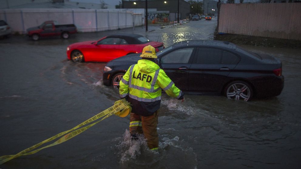 PHOTO: A firefighter carries caution tape in a flooded street as a powerful storm moves across Southern California Feb. 17, 2017, in Sun Valley, California. 