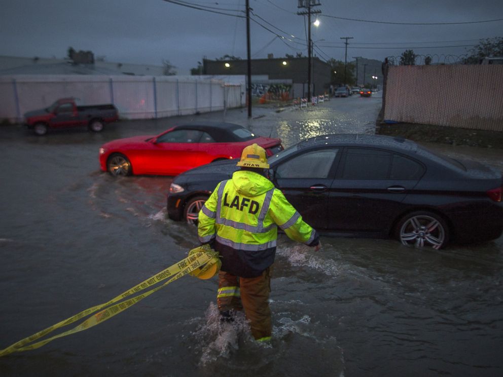 PHOTO: A firefighter carries caution tape in a flooded street as a powerful storm moves across Southern California Feb. 17, 2017, in Sun Valley, California.