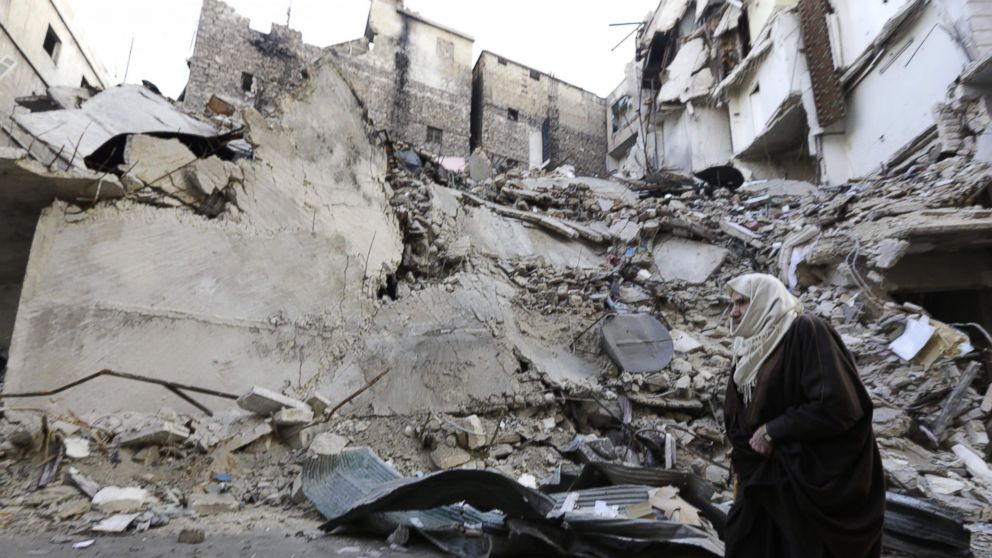 A Syrian woman walks past a destroyed building in Aleppo's formerly rebel-held al-Shaar neighborhood, Jan. 21, 2017, a month after government forces retook the northern Syrian city from rebel fighters. 