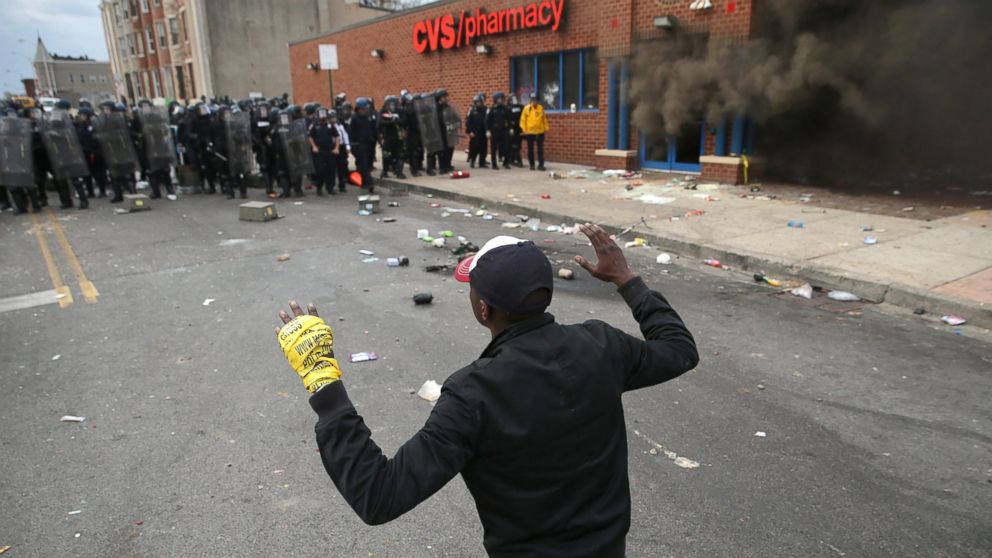 PHOTO: A man faces down a line of Baltimore Police as a CVS burns during violent protests following the funeral of Freddie Gray, April 27, 2015 in Baltimore. 