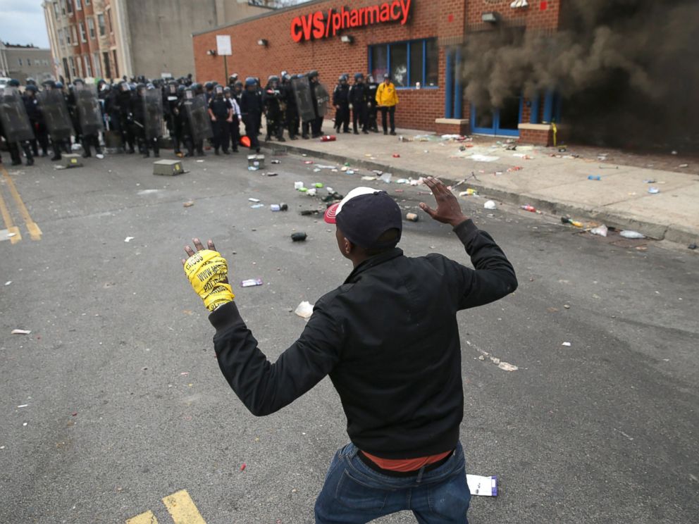 PHOTO: A man faces down a line of Baltimore Police as a CVS burns during violent protests following the funeral of Freddie Gray, April 27, 2015 in Baltimore.