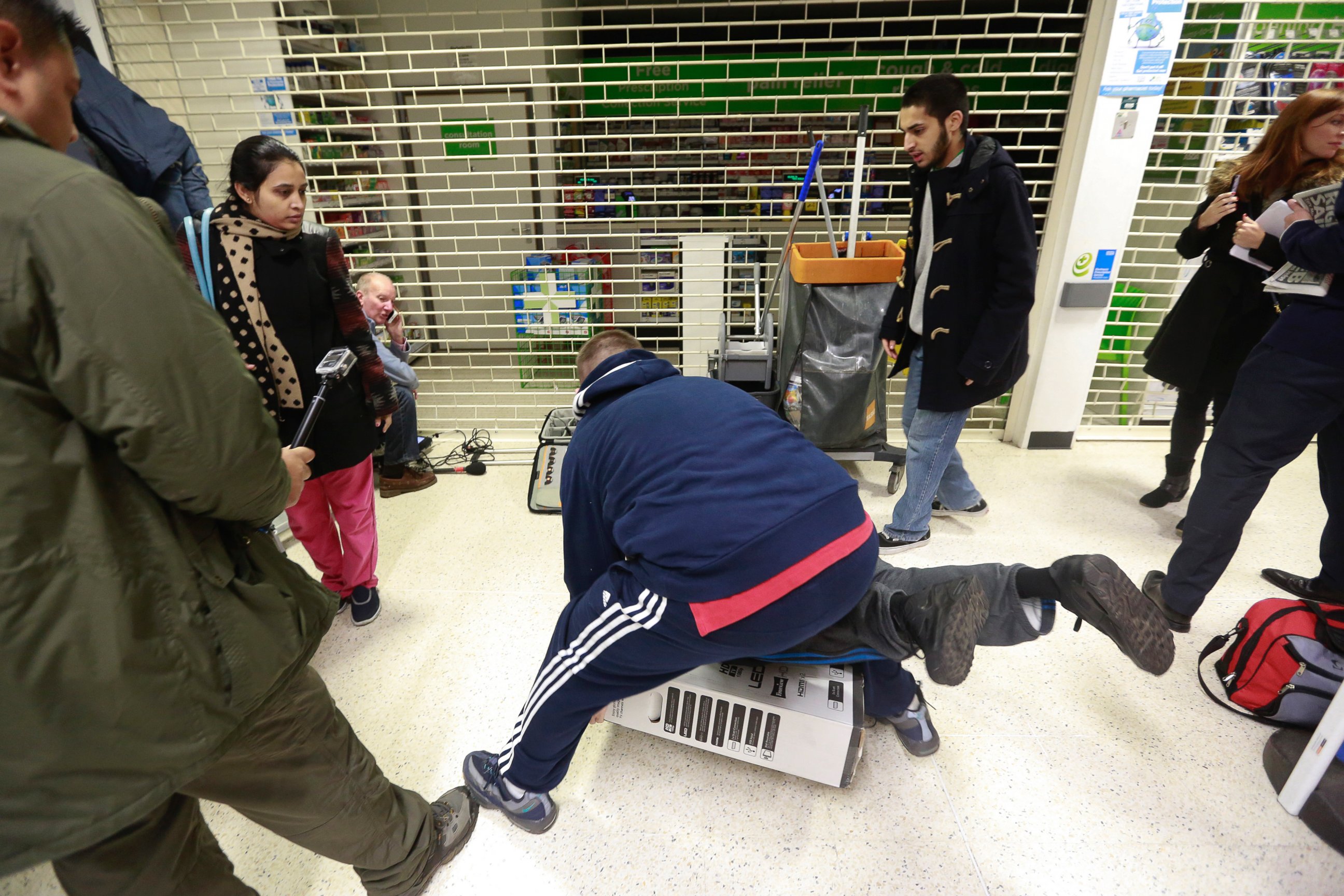 PHOTO: Customers fall to the floor as they grapple for an LED television during a Black Friday discount sale at an Asda supermarket in London on Nov. 28, 2014.