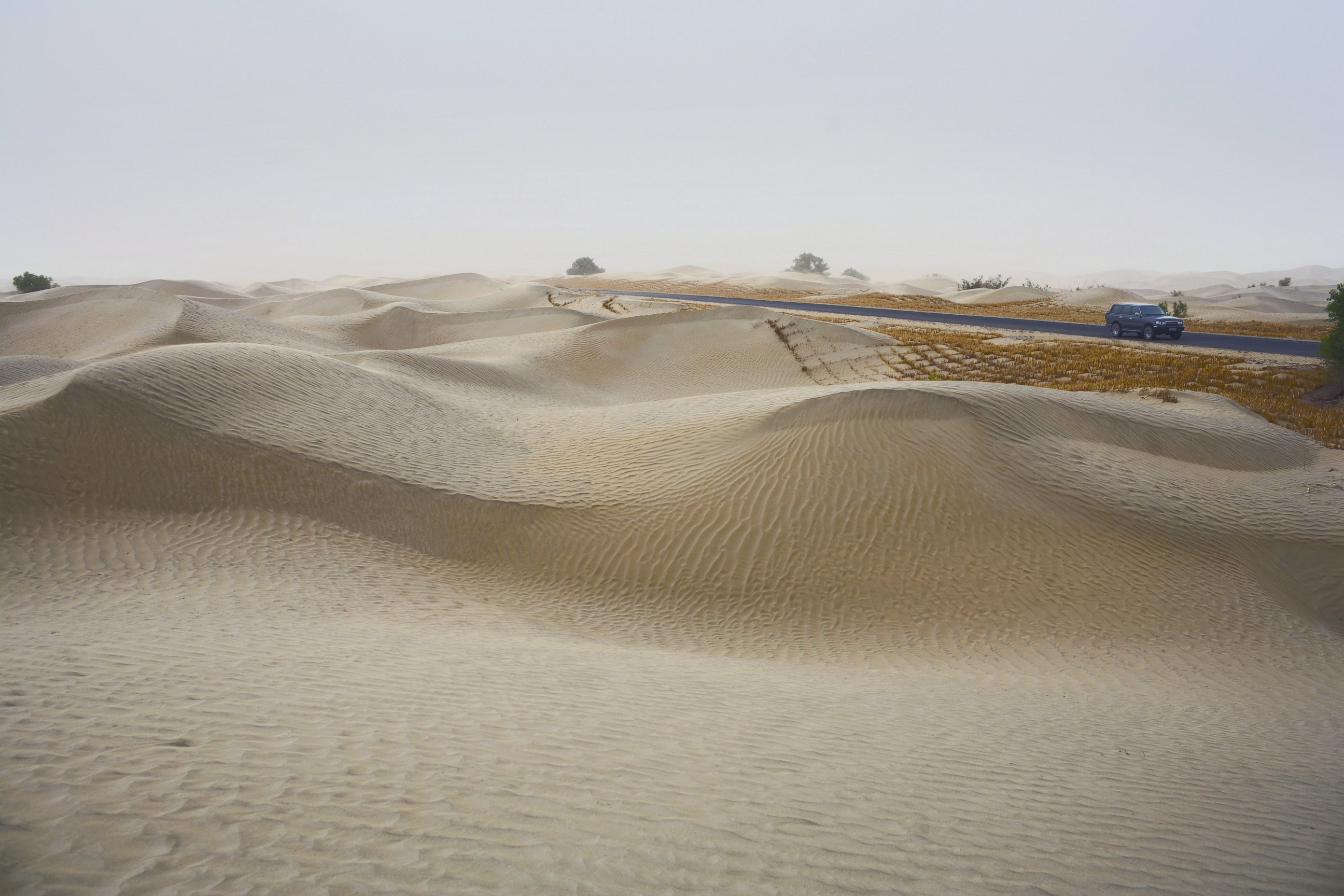 PHOTO:  A car drives past sand dunes on the newly built cross-desert highway on June 16, 2007 in the Taklamakan Desert.