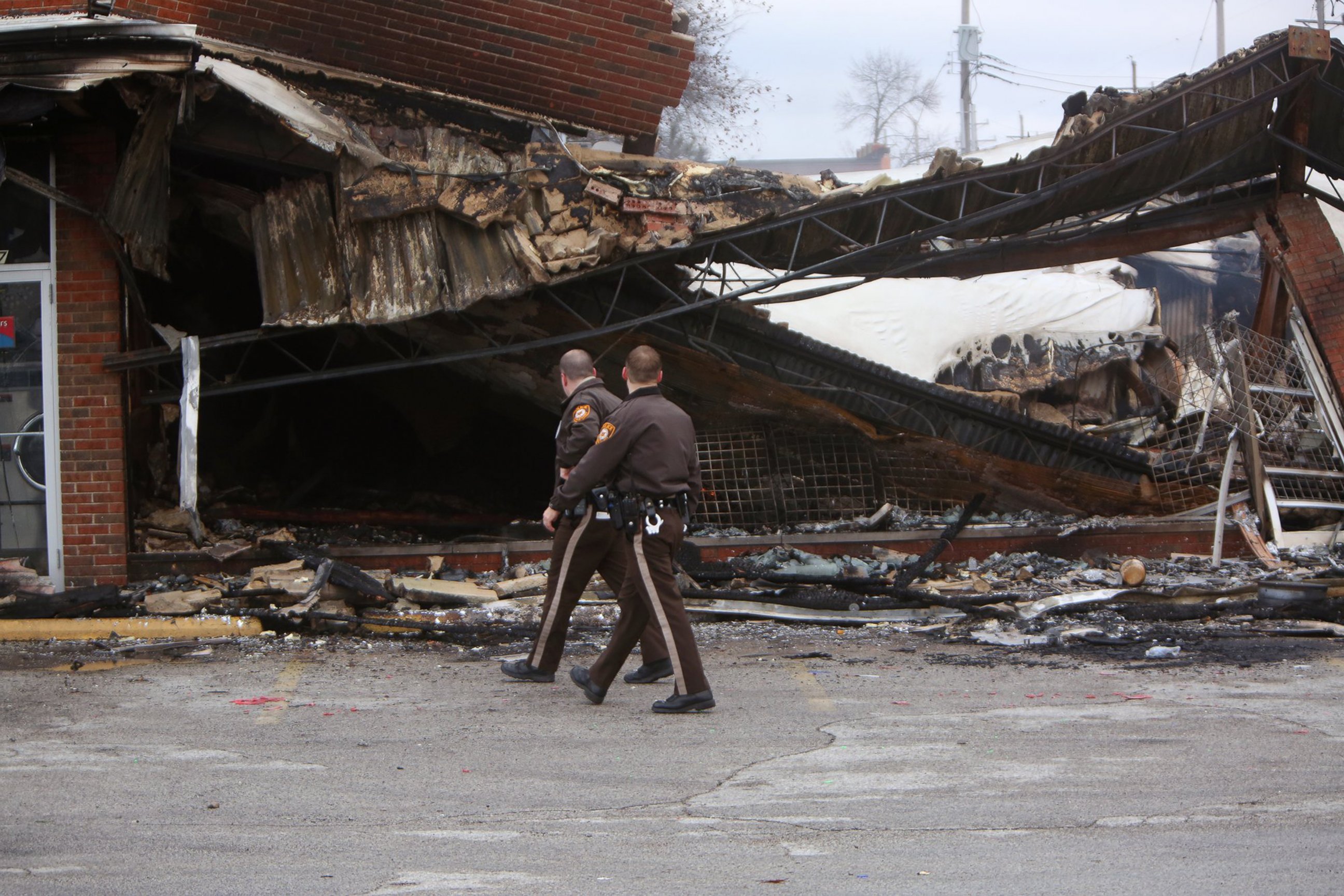 PHOTO: Police officers walk past the smoldering remains of a beauty supply store at the corner of Chambers Road and West Florissant Avenue, Nov. 25, 2014, in Ferguson, Mo. 
