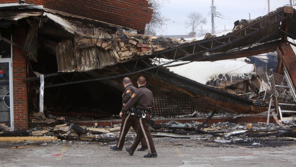 PHOTO: Police officers walk past the smoldering remains of a beauty supply store at the corner of Chambers Road and West Florissant Avenue, Nov. 25, 2014, in Ferguson, Mo. 
