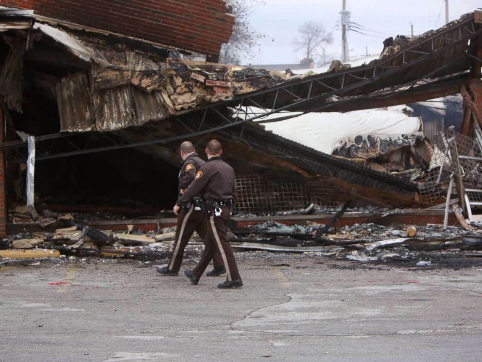 PHOTO: Police officers walk past the smoldering remains of a beauty supply store at the corner of Chambers Road and West Florissant Avenue, Nov. 25, 2014, in Ferguson, Mo.
