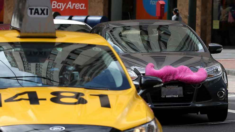 A Lyft car drives next to a taxi on June 12, 2014 in San Francisco, California.