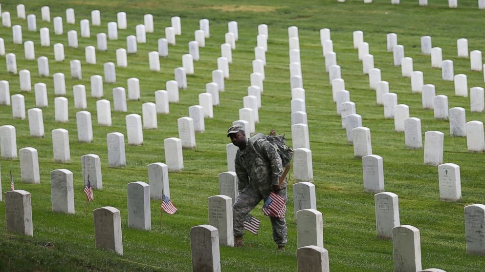 Members of the 3rd U.S. Infantry Regiment place American flags at the graves of U.S. soldiers buried at Arlington National Cemetery, in preparation for Memorial Day, in Arlington, Va., May 21, 2015.