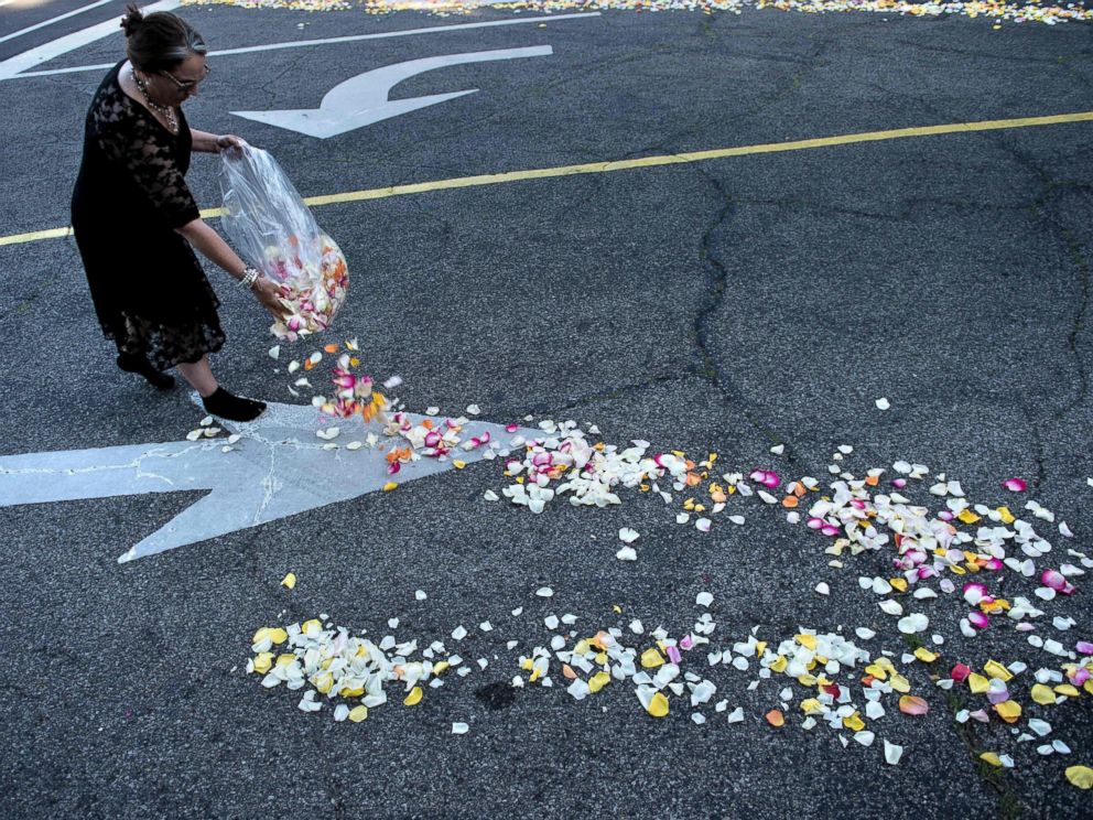 PHOTO: A woman places flower petals along the entrance to Cave Hill Cemetery for the funeral procession for boxing legend Muhammad Ali on June 10, 2016 in Louisville, Kentucky.
