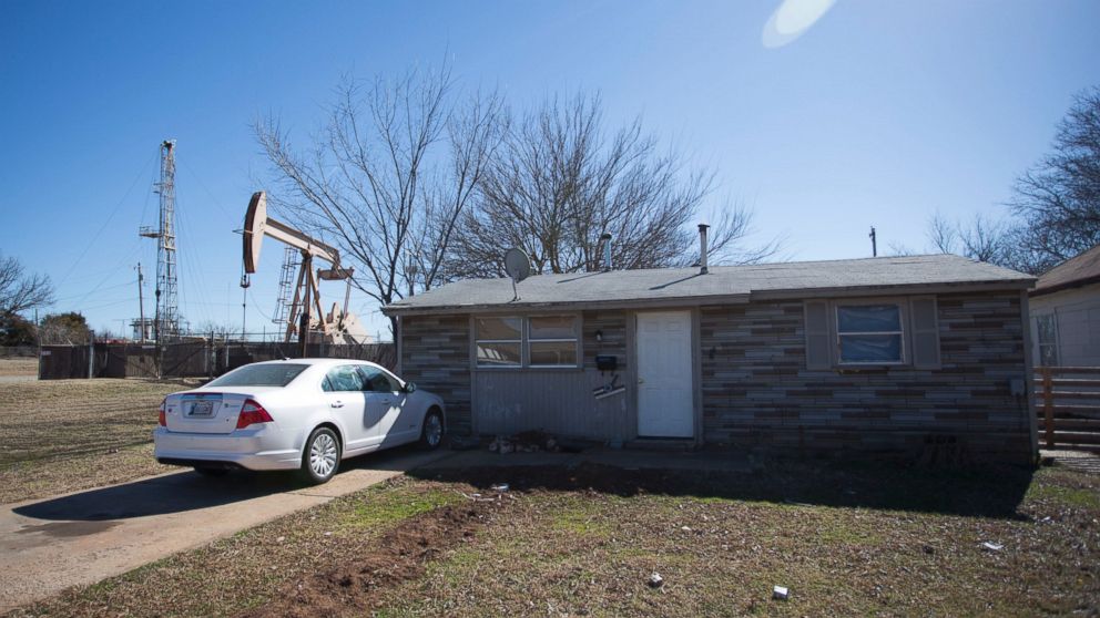 A new fracking rig and a pumping rig stand beside a house on February 10, 2016 in an Oklahoma City, Oklahoma neighborhood. Many believe the injection into deep underground wells of fluid byproducts from drilling operations is causing earthquakes.