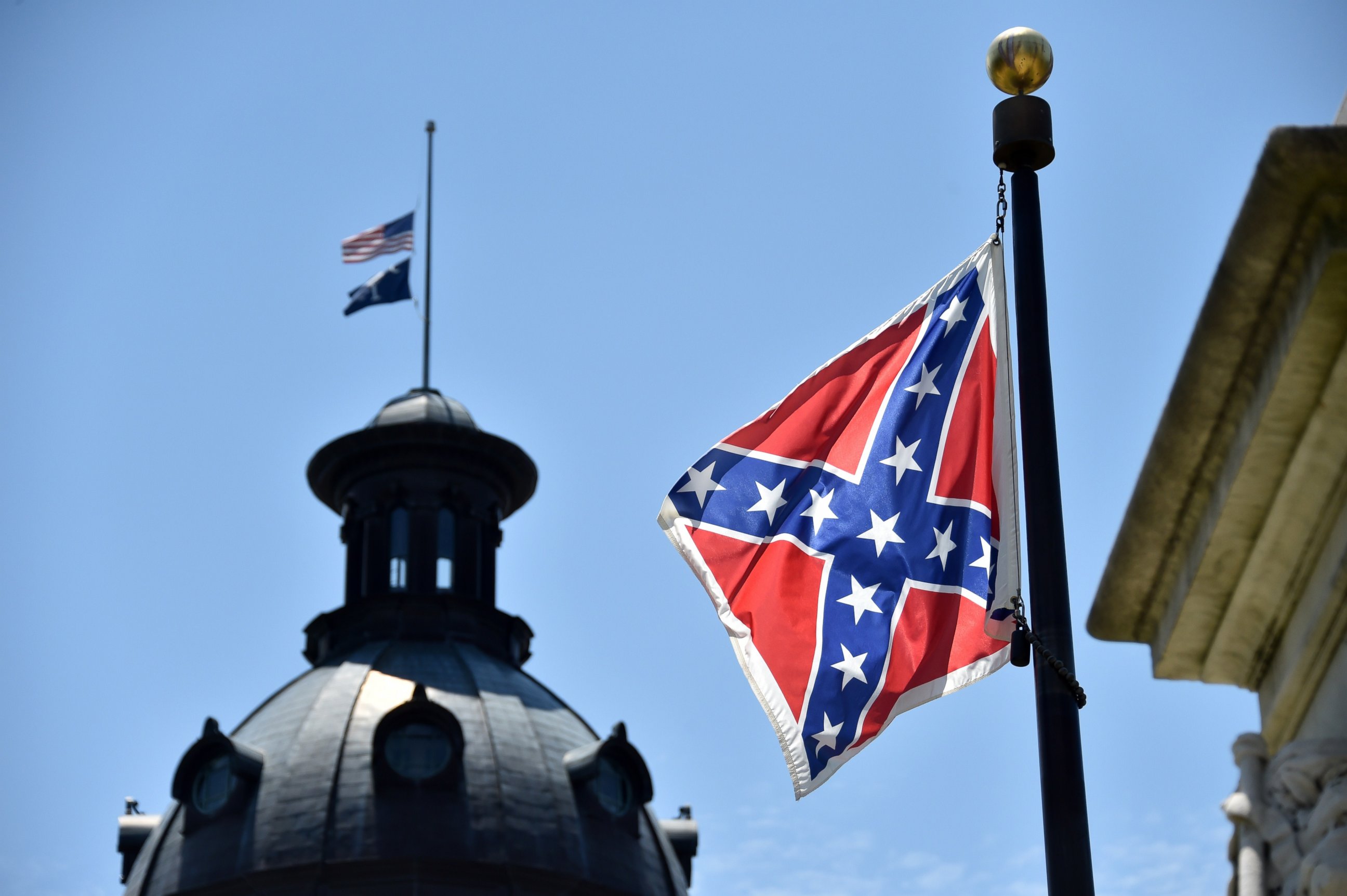 PHOTO: The South Carolina and American flags flying at half-staff behind the Confederate flag erected in front of the State Congress building in Columbia, South Carolina on June 19, 2015. 