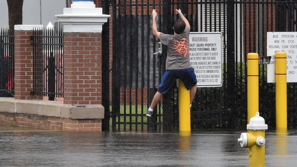 PHOTO: A boy tries to stay on dry by climbing along a fence on a flooded street in downtown Charleston, South Carolina on Oct. 4, 2015.