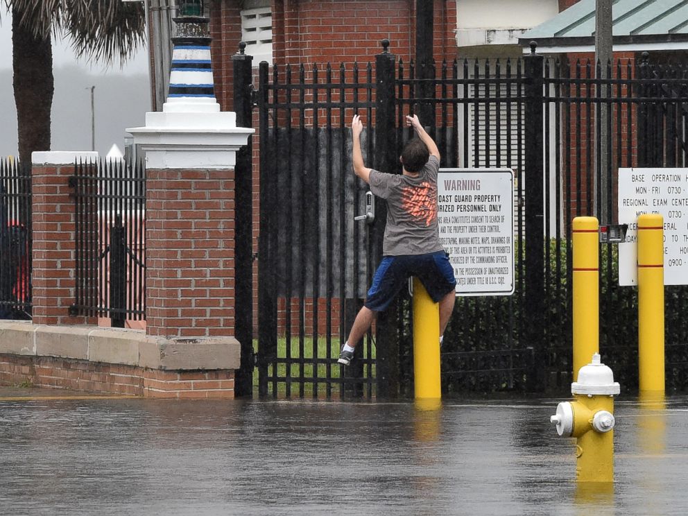 PHOTO: A boy tries to stay on dry by climbing along a fence on a flooded street in downtown Charleston, South Carolina on Oct. 4, 2015.